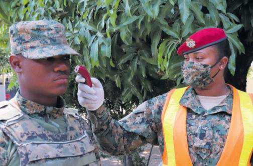 A member of the Jamaica Defence Force conducts a temperature check on a colleague.